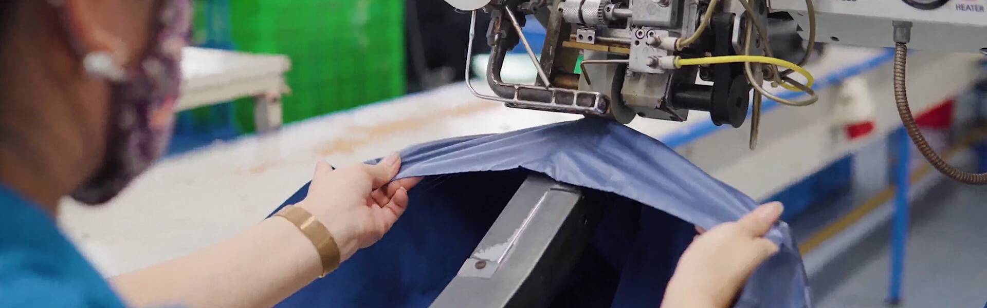 A person sewing a piece of blue color fabric